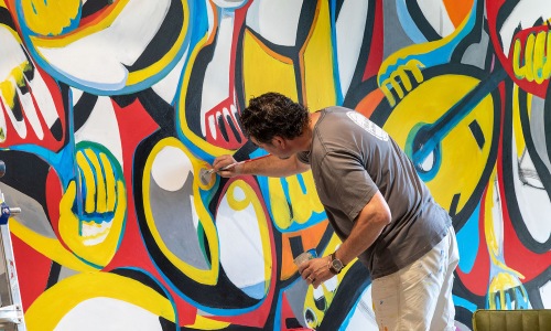 A Man painting a very bright wall mural 